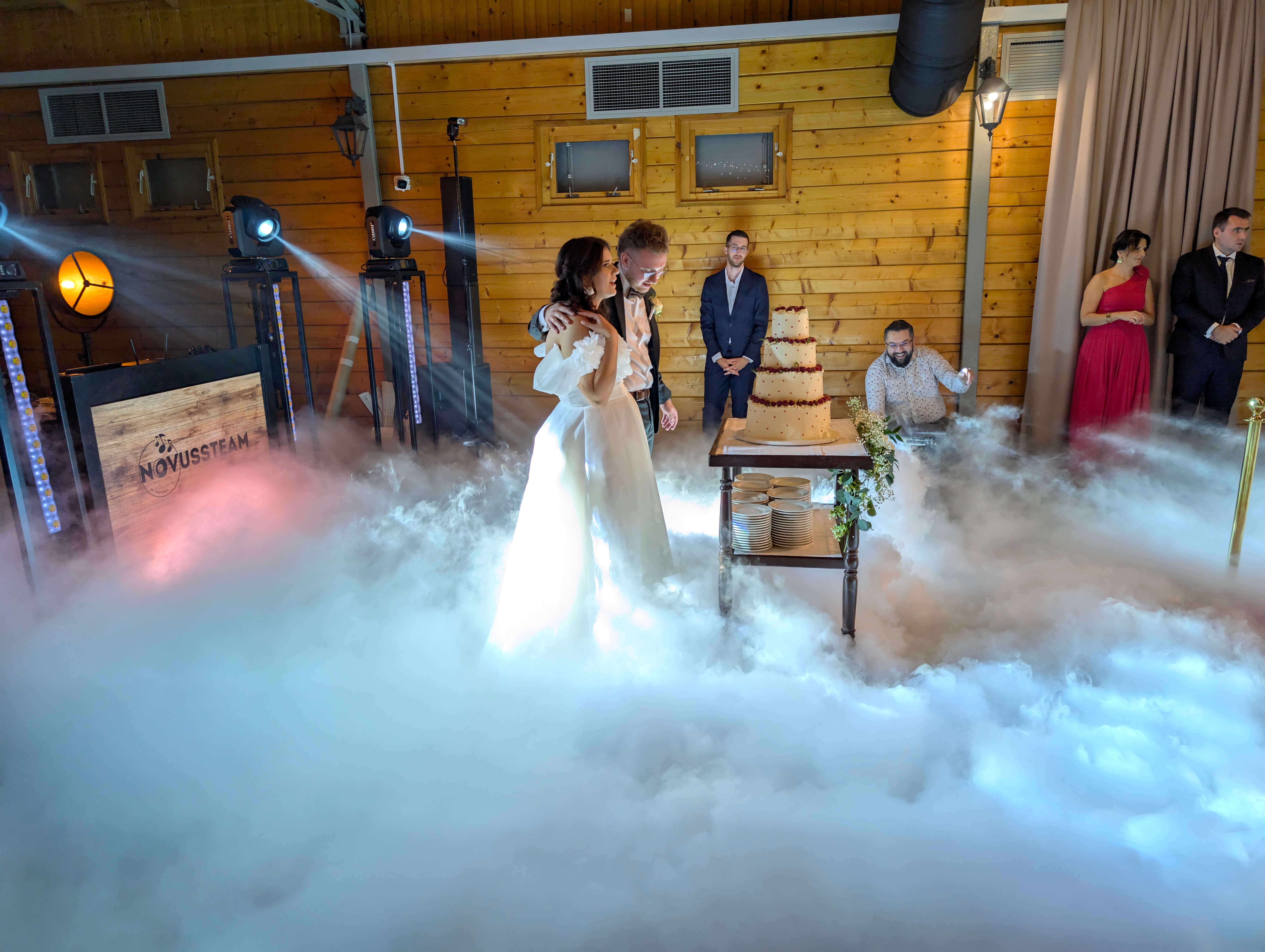 Para młoda podczas pierwszego tańca otoczona dramatycznymi efektami dymu w rustykalnej sali