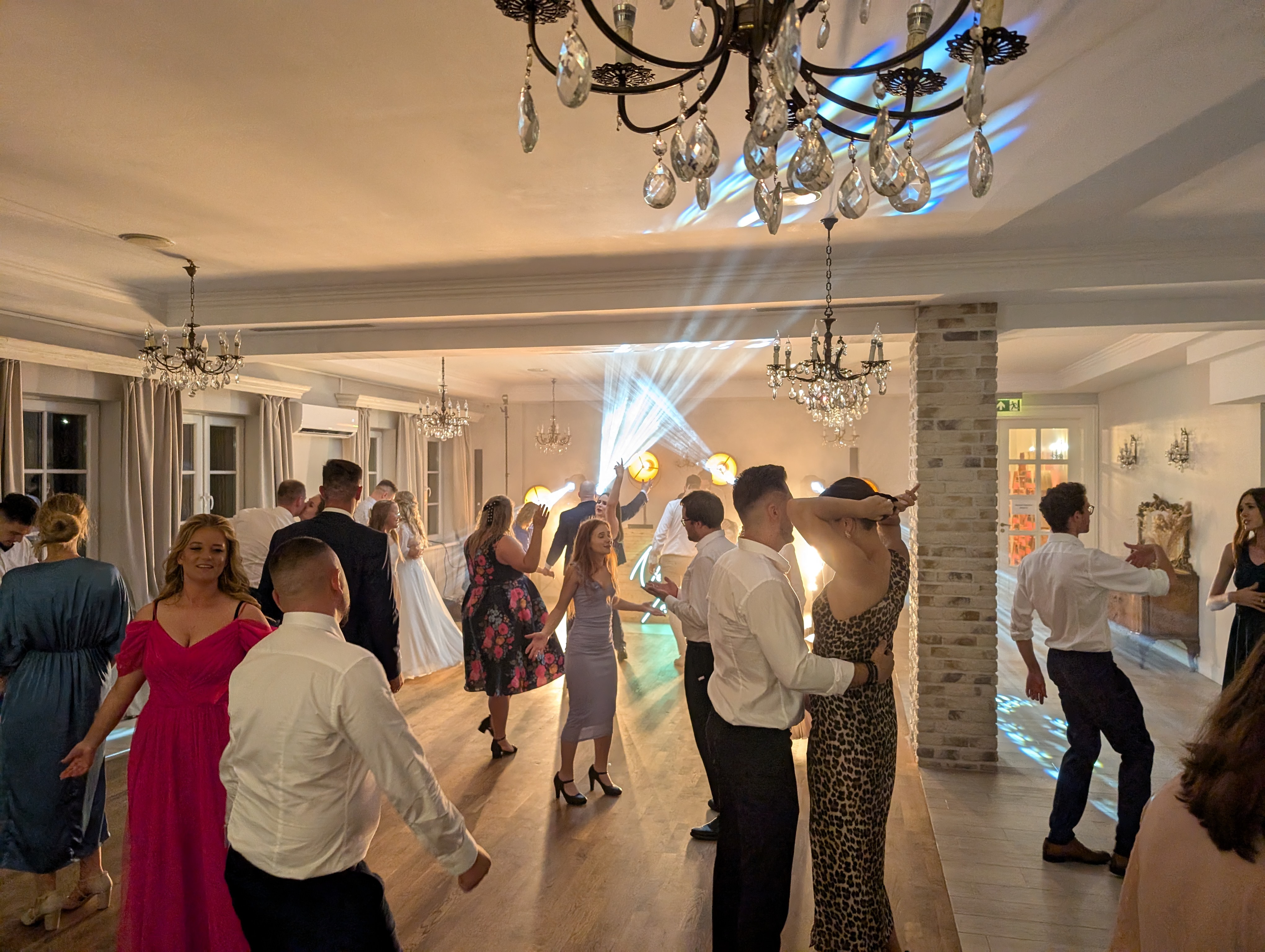 Elegancka sala balowa z tańczącymi gośćmi i kryształowymi żyrandolami