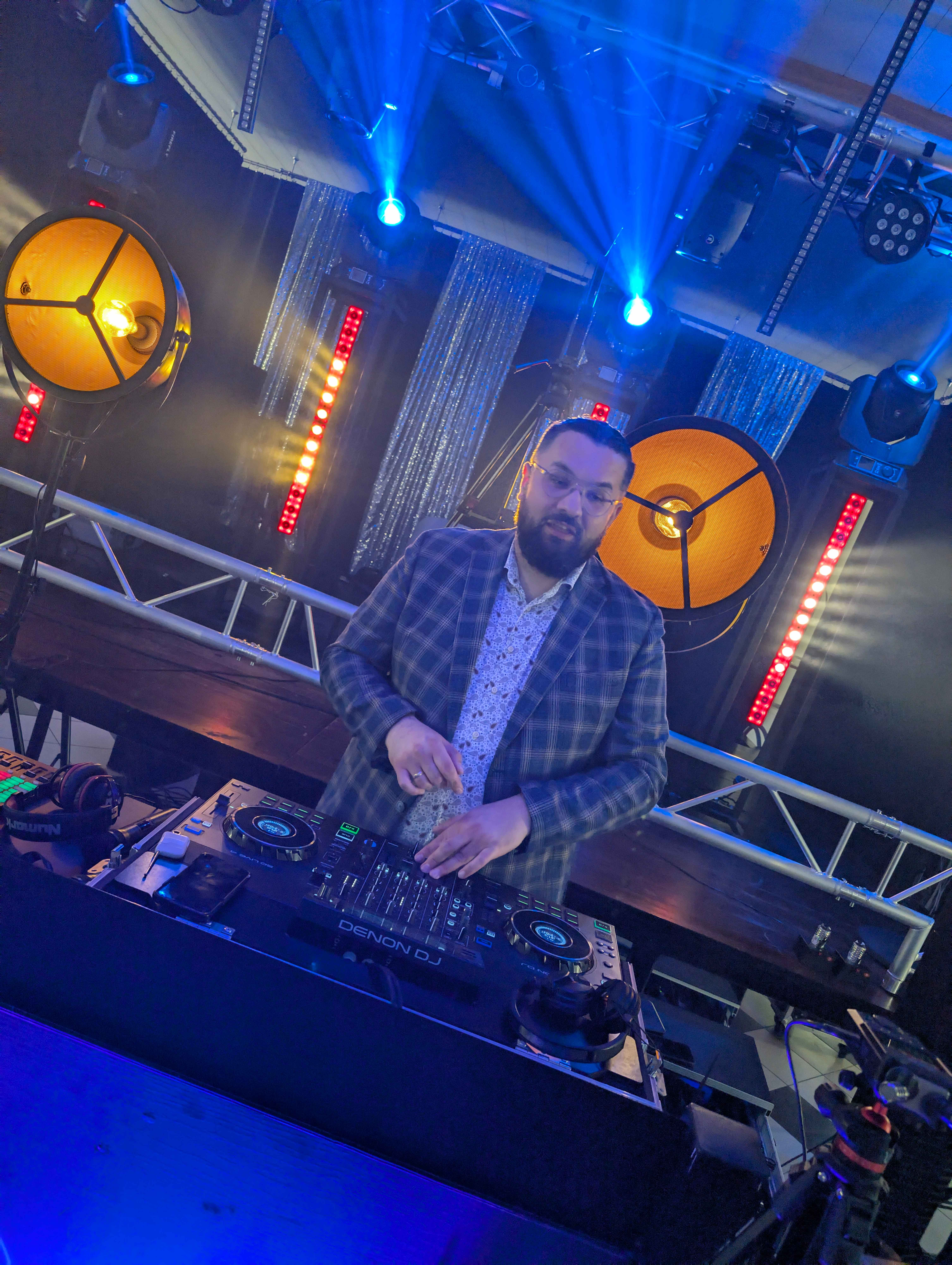 DJ na podwyższonej platformie z dramatycznym niebieskim oświetleniem